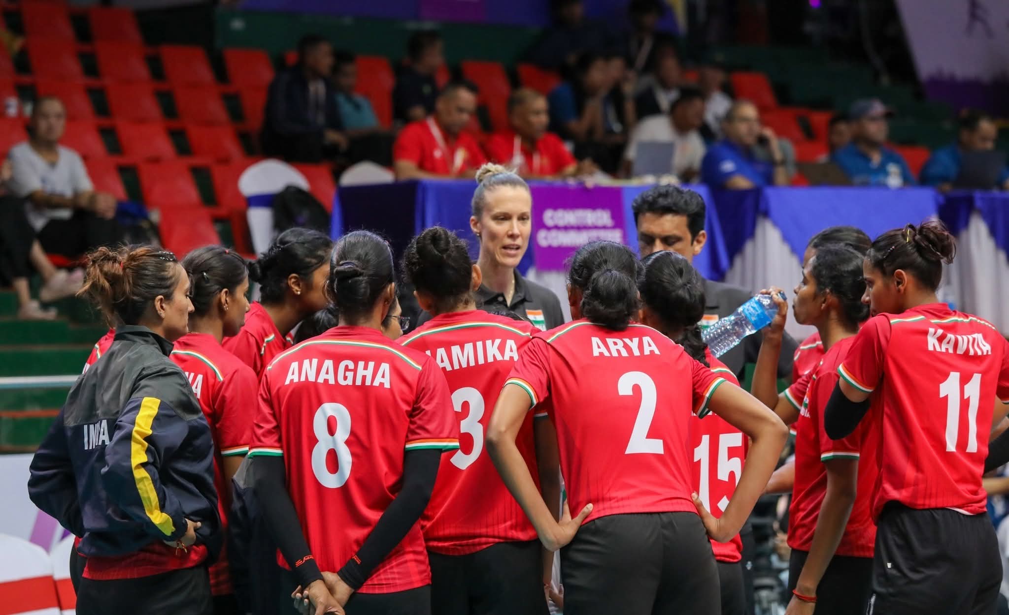 Jana Kulan coaching a volleyball team during a huddle